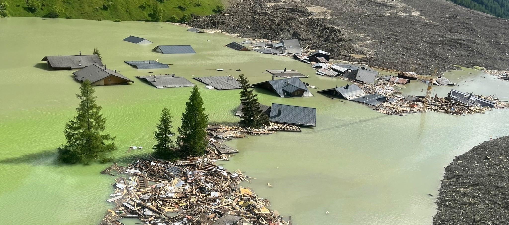 Bild des Bergsturzes in Blatten zeigt, wie Häuser unter Wasser stehen.