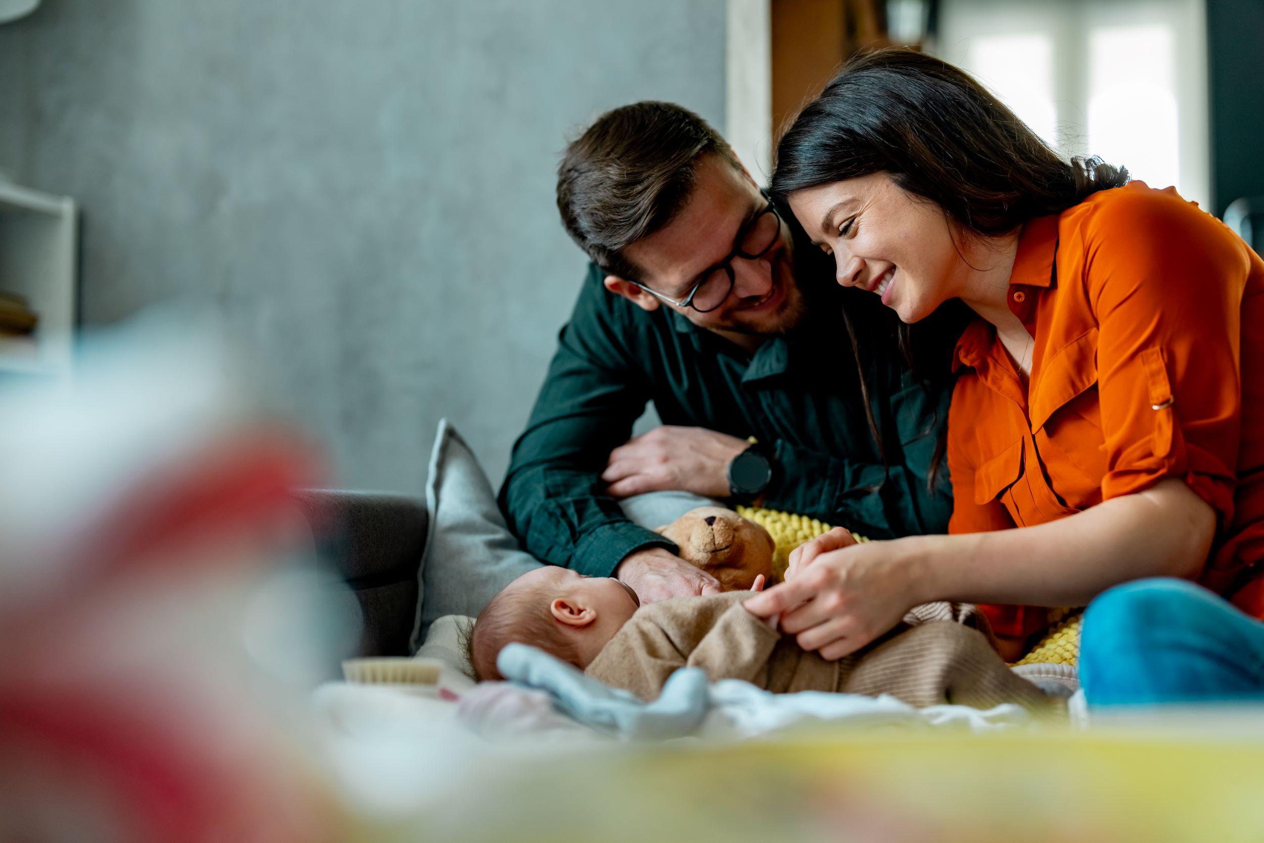 Paar über Baby gebückt am Lächeln