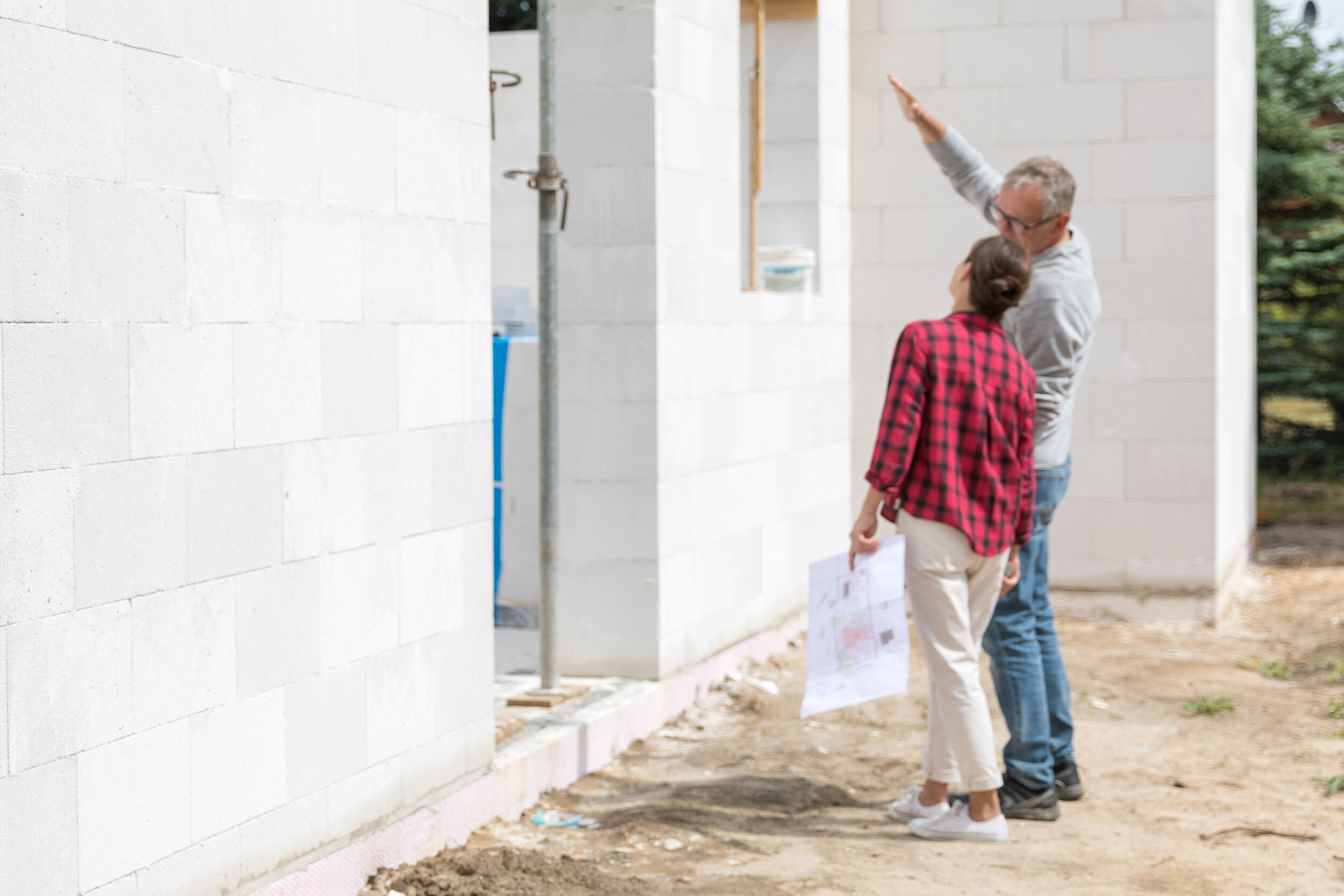 Paar steht vor einem Haus, dass sich im Bau befindet